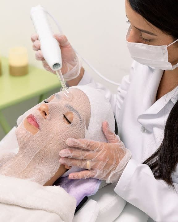 Esthetician performing a facial treatment with a high-frequency wand